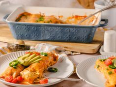 two white plates topped with enchiladas next to a casserole dish