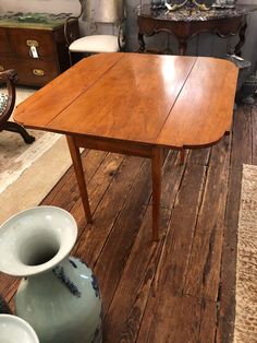 a wooden table sitting on top of a hard wood floor next to two vases