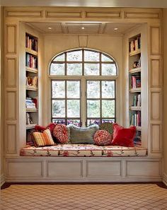 an image of a couch in front of a window with bookshelves on it