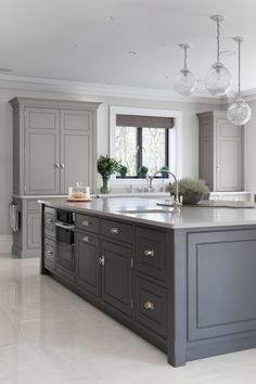 a large kitchen with gray cabinets and marble counter tops, along with an island in the middle