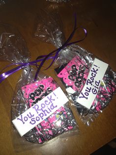 some pink and black cookies wrapped in cellophane with purple ribbon on the top