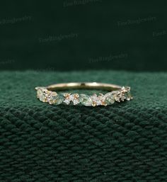 a gold ring with three stones on it sitting on top of a green cloth covered surface