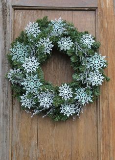 a wreath with snowflakes is hanging on a wooden door