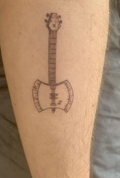 a guitar tattoo on the leg of a man's leg, with an arrow in the middle