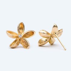 two gold flower shaped earrings with diamonds on each earring, one in the shape of a flower