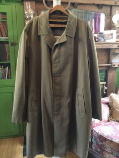 Made by Croydon, this beautiful men's overcoat has the original buttons down the front under the placket, matching buttons on the cuffs, two outside pockets and one inside pocket. It is lined with a colourful silky plain lining, but the removable heavier lining is missing. This doesn't affect the wearability of the coat. In very good condition. The measurements, taken with the coat lying flat, are: shoulder to shoulder, 20 inches; armpit to armpit, 26 inches; sleeves, 26 inches; total length, 42 inches; bottom edge, 30 inches. Single Breasted Long Khaki Pea Coat, Khaki Single-breasted Long Pea Coat, Green Outerwear With Pockets For Rainy Weather, Classic Green Outerwear For Outdoor, Green Outerwear With Button Closure For Business, Classic Green Outdoor Outerwear, Green Business Outerwear With Button Closure, Classic Long Winter Raincoat, Classic Green Pea Coat With Button Closure