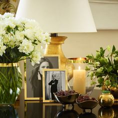 a table topped with vases filled with flowers next to candles and pictures on the wall