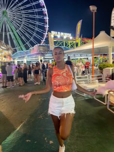 a woman walking down the street in front of a ferris wheel