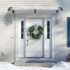 a white front door with a wreath on it and the words midea above it