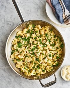 a skillet filled with pasta and garnished with parsley on the side