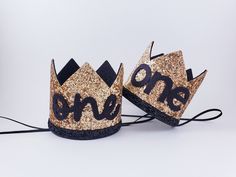 two black and gold crowns with the word one on them sitting next to each other