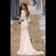 a woman in a white dress is standing on the steps and looking down at something