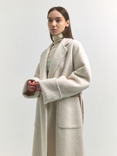 Editor's Notes Woven from suri alpaca blend wool fabric, this relaxed fit coat has minimalistic, luxurious silhouette. It is accentuated with voluminous, hairy texture and rolled-style cuffs. - Soft and cozy alpaca blend coat- Intended for a loose fit- Comfortable dropped shoulders- Detachable waist strap detail- Wide out pockets- Back slit detail for added flexibilityMeasurements(in.)Size One Size(XS-M)- Length: 43.90 in - Shoulder: 21.46 in - Bust: 21.54 in - Hem: 24.41 in - Sleeve length: 27.36 in - Sleeve width: 8.66 in - Sleeve hem: 7.48 in * Model info: Height 5' 7 Bust 33 Waist 25 Hip 34.5 / Height 5' 6 Bust 32 Waist 24 Hip 35 Composition & Care- 51% Wool, 38% Suri Alpaca, 6% Alpaca, 5% Nylon / Lining: 100% Polyester - Dry C Suri Alpaca, Fitted Coat, Waist Strap, Wool Fabric, Alpaca, Hand Made, Loose Fitting, Relaxed Fit, Sleeve Length