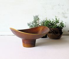 two wooden bowls sitting next to each other on top of a white table with plants in them