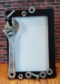 a wrench and screwdriver frame sitting on a wooden table in front of a brick wall