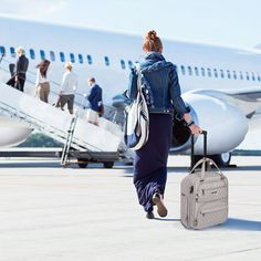 a woman walking towards an airplane with her luggage