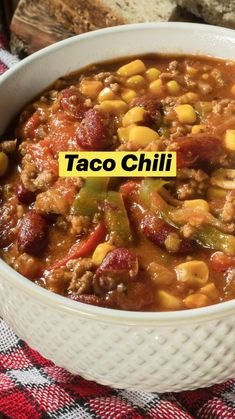 a white bowl filled with chili and corn on top of a red checkered table cloth