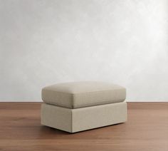 a footstool sitting on top of a wooden floor next to a white wall