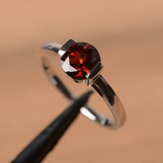 It is a natural garnet ring. The main stone is 7 mm*7 mm round cut.weight about 1.68 carats.The basic metal is sterling silver and plated with rhodium.To change the metal to a solid gold (white/rose) or platinum is also available, please ask for a quotation if you want.You can also go to my shop Home for more elegant rings: https://www.etsy.com/shop/godjewelry?ref=hdr_shop_menu Garnet is the January birthstone More garnet rings:https://www.etsy.com/shop/godjewelry?section_id=20709242Customizatio Classic Garnet Solitaire Rings, Classic Solitaire Garnet Ring, Fine Jewelry Garnet Solitaire Ring, Classic Ruby Ring With Tension Setting, Classic Round Ruby Ring With Tension Setting, Round Garnet Solitaire Ring, Garnet Solitaire Rings, Classic Garnet Round Cut Ring, Classic Solitaire Jewelry With Lab-created Ruby