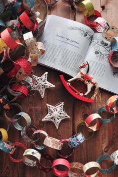 an open book sitting on top of a wooden floor next to ribbons and other decorations