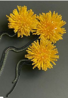 two yellow flowers are on a black beaded chain and one is in the shape of a snake