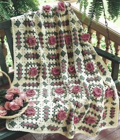 a crocheted blanket on a bench with pink flowers