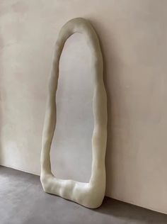 a large white sculpture sitting on top of a floor next to a wall with a mirror in it