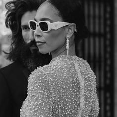 a woman wearing white sunglasses standing next to a man