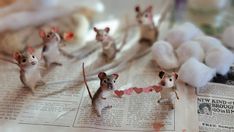 small mouses sitting on top of a newspaper next to cotton balls and other items