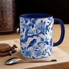 a blue and white coffee mug sitting on top of a wooden table next to a cookie