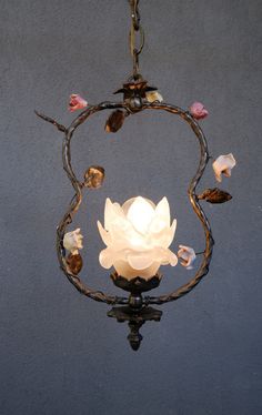 a chandelier hanging from a ceiling with flowers on the top and leaves around it