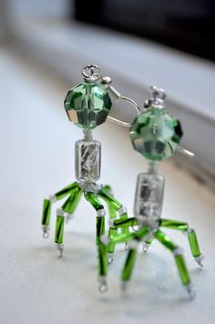 green and clear glass spider earrings on a window sill