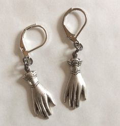 A pair of elegant hands two hand earrings created from two Victorian styled findings silver tone charms. These earrings hang from the cuff For pierced ears with leverback fittings Perhaps a present for an engagement or wedding with the emphasis on hands in both celebrations.  Please note that the hands are identical and therefore not a true 'pair' of hands, but good for giving a virtual hug The charms are single sided stamped metal and are therefore hollow backed and lovely and light to wear Measurement hand 2.5cm long each  See other hand and eye jewellery Silver Clip-on Dangle Jewelry, Silver Dangle Clip-on Jewelry, Silver Clip-on Earrings With Lever Back For Gift, Silver Clip-on Earrings With Lever Back As A Gift, Silver Dangle Hoop Earrings With French Hook, Silver Hoop Earrings With French Hook, Silver French Hook Jewelry For Wedding, Adjustable Silver Jewelry With Lever Back, Silver Lever Back Jewelry Gift