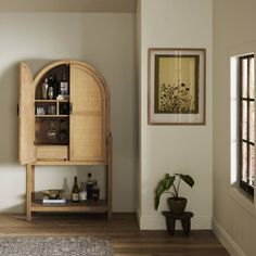 a wooden cabinet sitting in the middle of a living room next to a door and window