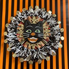 a black and white cat mask with gold accents on it's face, sitting in front of an orange striped background