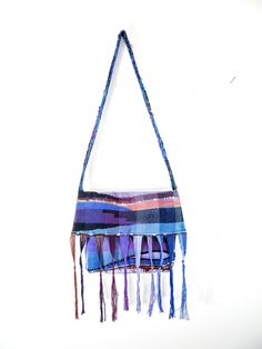 a multicolored handbag hanging on a wall with tassels around it