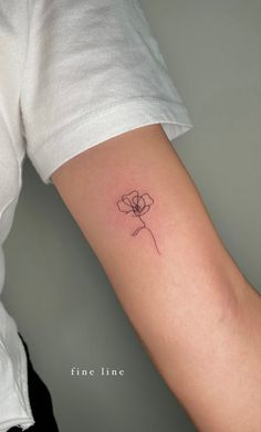 a woman's arm with a single flower tattoo on the left side of her arm