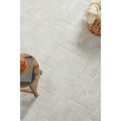 a white tile floor with a basket on the side and an orange chair next to it