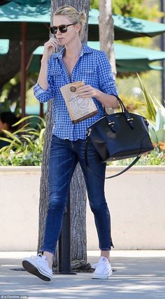 a woman talking on her cell phone while walking down the street with a handbag