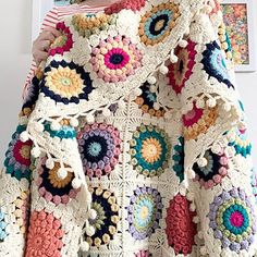 a crocheted granny's jacket is hanging on a wall