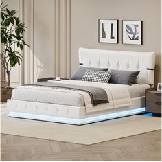 a white bed sitting on top of a wooden floor next to a plant in a room