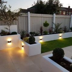 an outdoor garden with white planters and lights