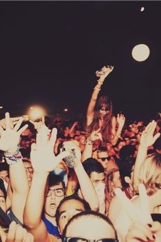 a group of people at a concert with their hands in the air and one person holding up his cell phone