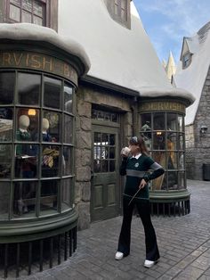 a woman standing in front of a harry potters house with her hand on her hip