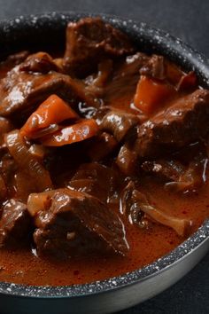 a bowl filled with meat and carrots on top of a table