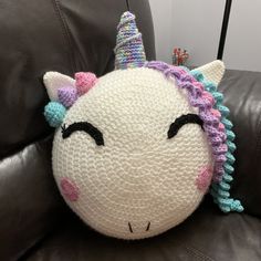 a crocheted unicorn pillow sitting on top of a leather chair