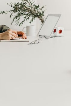 a woman is typing on her laptop while sitting at a desk with a plant in the background