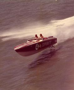 two people in a speed boat riding on the water with another person behind them watching