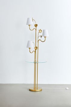 a floor lamp with three lamps on each side and a glass table top underneath it