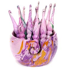 a purple bowl filled with lots of pink and white marbled objects on top of each other